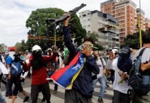 Opositores muestran una escopeta que arrebataron a la policía durante una manifestación en Caracas, el 3 de mayo de 2017 (Foto: Carlos García Rawlins / Reuters)