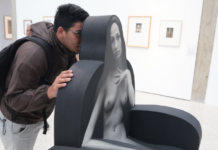 «Sin Censuras»: El desnudo en el arte venezolano rompe tabúes Un joven con mochila y gafas mira curiosamente una escultura interactiva en una galería de arte moderna.